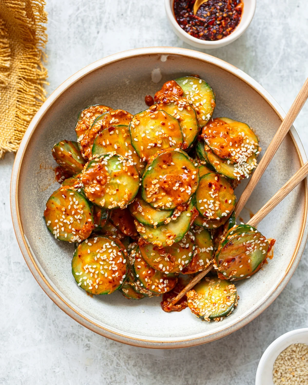 Cucumber salad coated in spicy peanut dressing and sesame seeds in a serving bowl